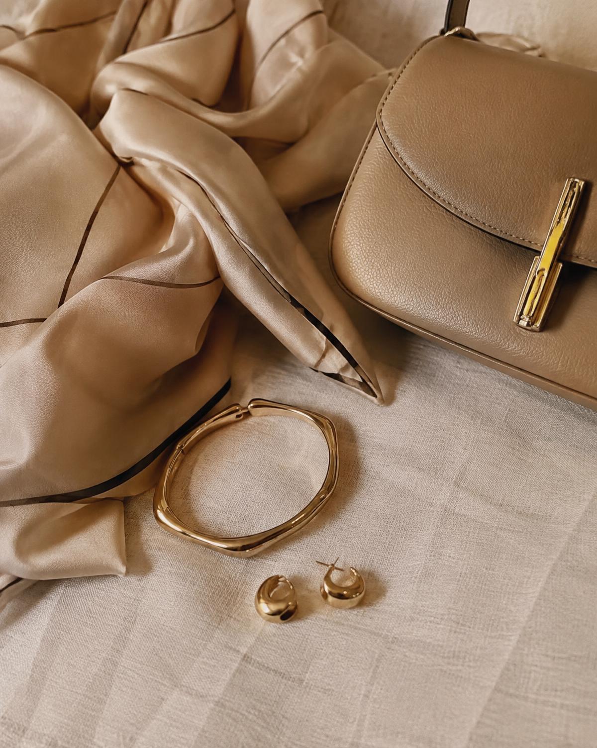 Details: zijden sjaal, gouden sieraden en een tas in beige tinten
